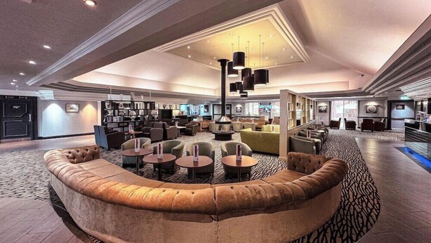 A spacious lobby with a curved seating area, multiple tables, and a high ceiling with recessed lighting. - Doubletree Newbury North (Newbury)