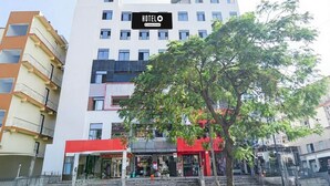 A hotel with a signboard, a red storefront, and a tree in the foreground.