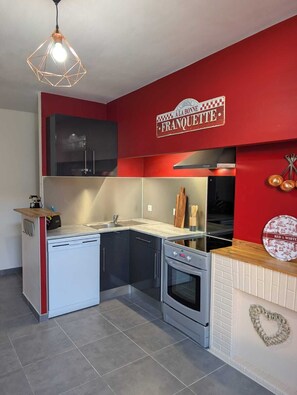 A compact kitchen with a dishwasher, oven, and a red accent wall. - Town house in Lot et Garonne with private courtyard (Seyches)