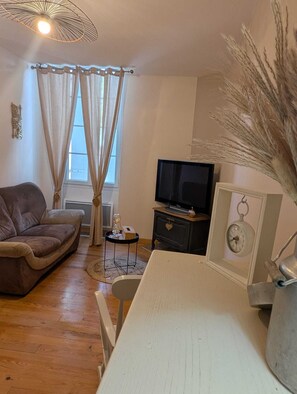 A living room with a sofa, TV, decorative wall piece, and a clock. - Town house in Lot et Garonne with private courtyard (Seyches)