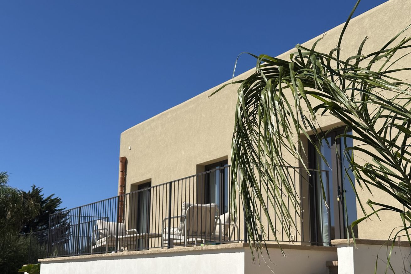 A building with a balcony, a chair, and a potted plant.