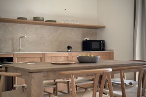 Eine moderne Küche mit Holztisch und -stühlen, einer Mikrowelle und einer Kaffeemaschine.