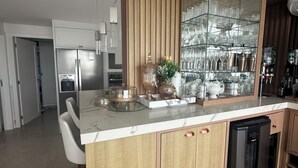 Une cuisine moderne dotée d’un îlot central intégré, d’appareils électroménagers en acier inoxydable et d’un meuble vitrine.