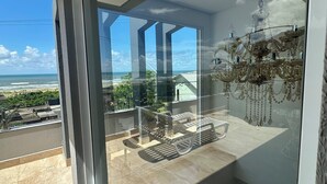 Un balcon avec vue sur l’océan, un lustre et un aménagement intérieur moderne.