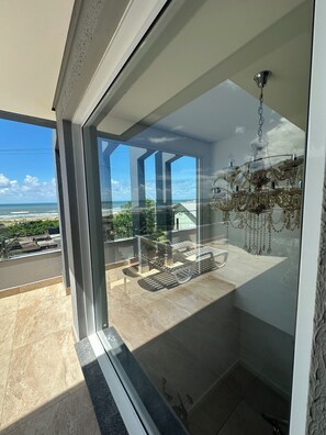 Un balcón con vista al océano, un candelabro y un diseño interior moderno.