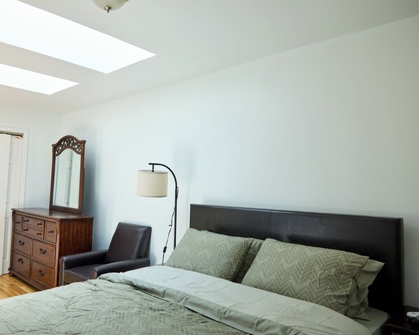 Une chambre à coucher avec un lit, une commode, une chaise, une lampe et un miroir.