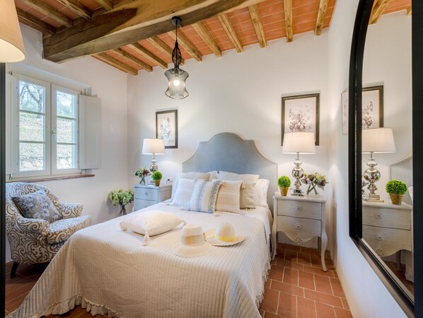 Ein Schlafzimmer mit einem Bett, Nachttischen, einem Sessel und einem Fenster.