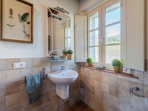 Ein Badezimmer mit Waschbecken, Spiegel und Fenster.