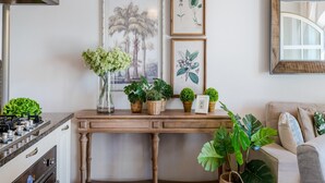 Eine Küche mit Herd, Backofen und einem Holztisch, dekoriert mit Pflanzen und botanischen Drucken.