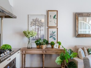 Eine Küche mit Herd, Backofen und einem Holztisch, dekoriert mit Pflanzen und botanischen Drucken.