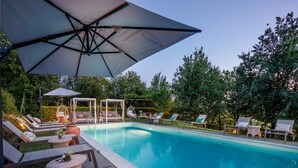 Ein Schwimmbecken mit Liegestühlen und Sonnenschirmen.