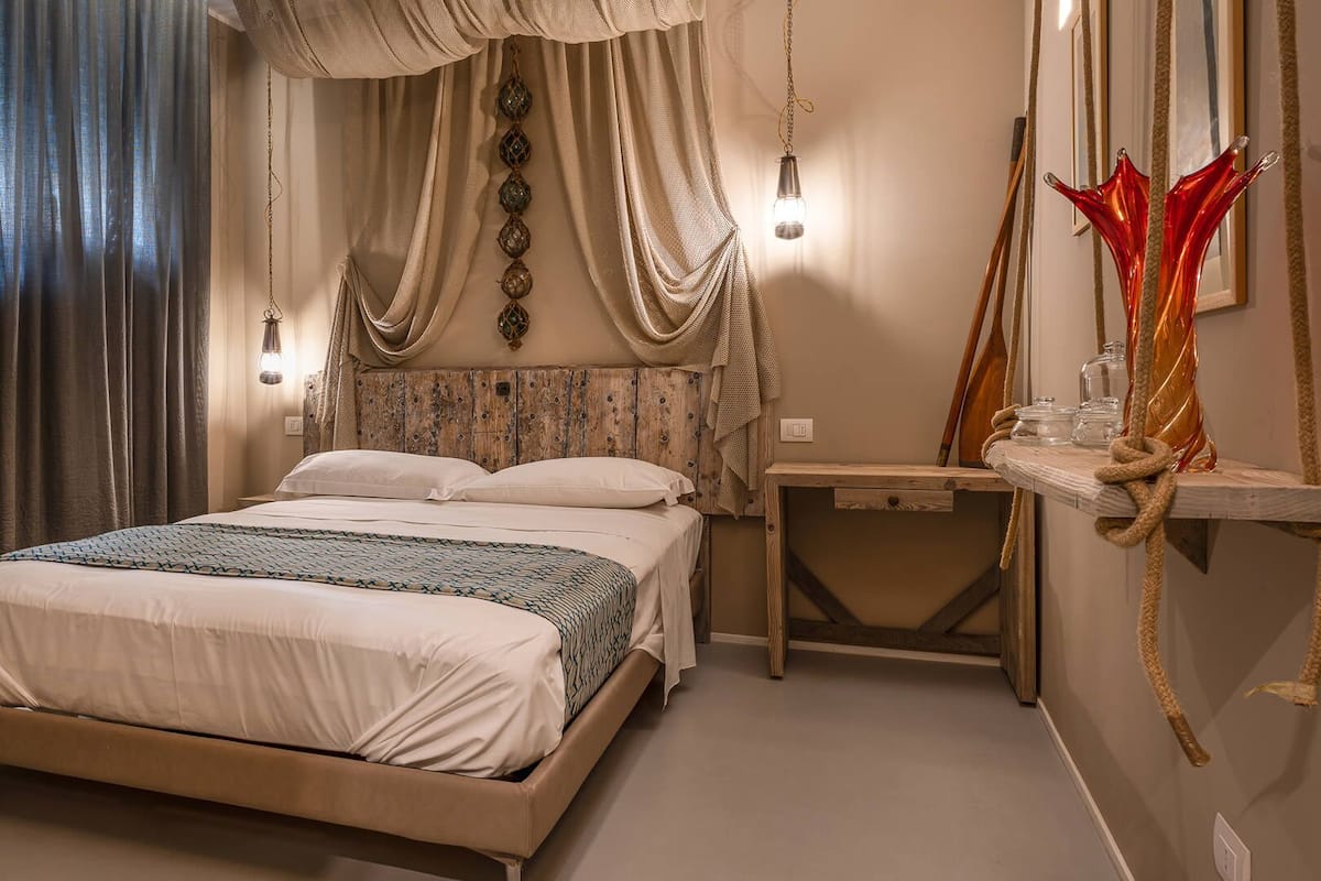 A bedroom with a bed, bedside table, and a wall-mounted shelf with decorative items.