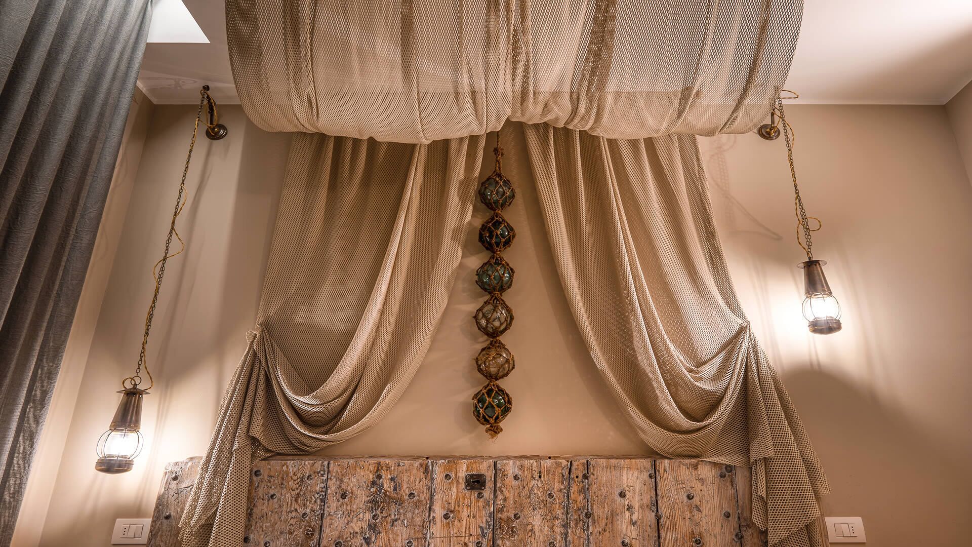 A room with a wooden headboard, draped curtains, and pendant lights.
