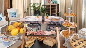 Ein Frühstücksbuffet mit verschiedenen Speisen, einer Pflanze und einem Bücherregal im Hintergrund.