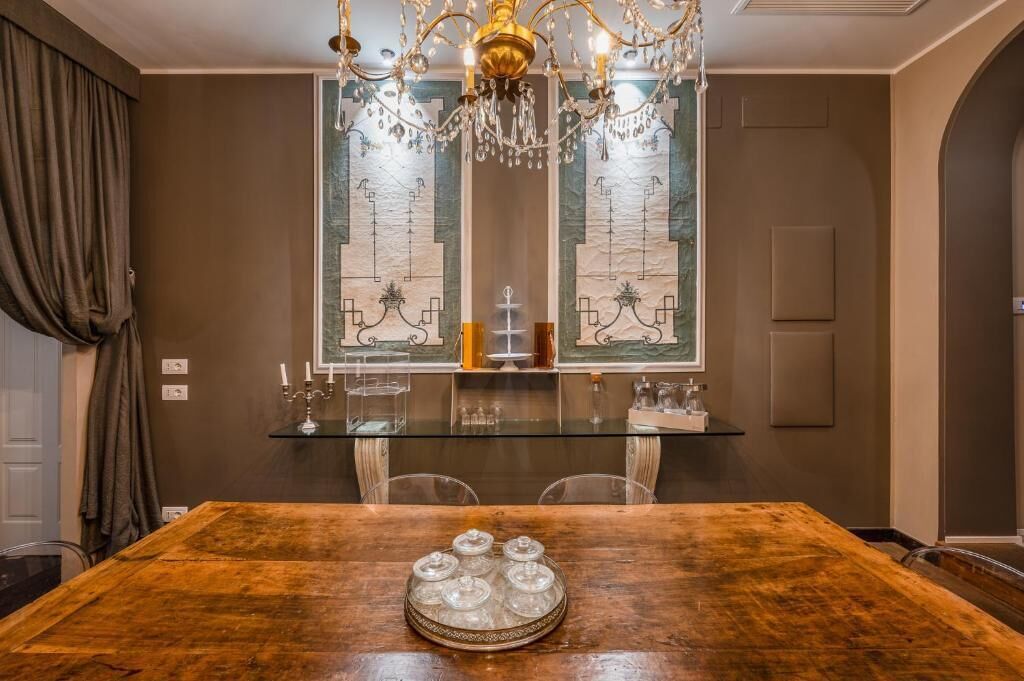 Een eetruimte met een houten tafel, een glazen blad en een kroonluchter.