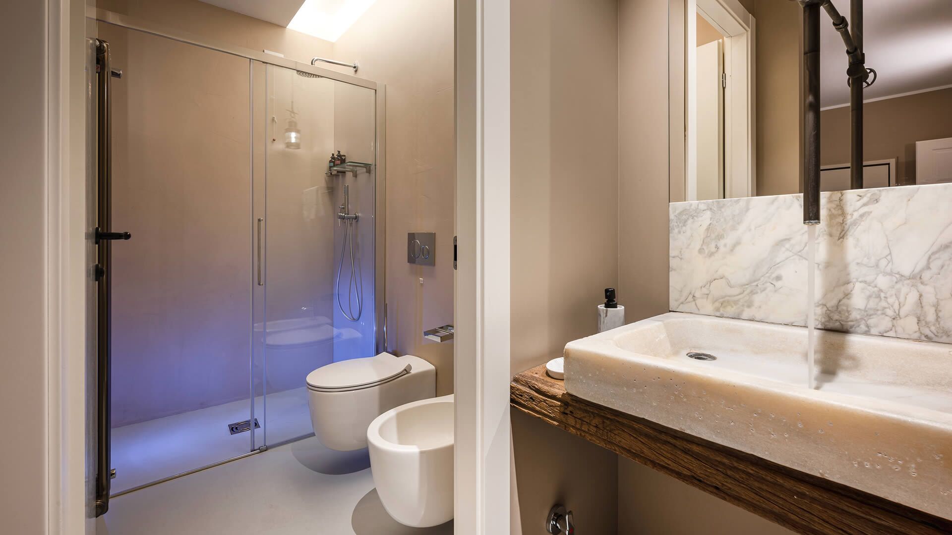A modern bathroom with a glass-enclosed shower, a toilet, and a marble sink.