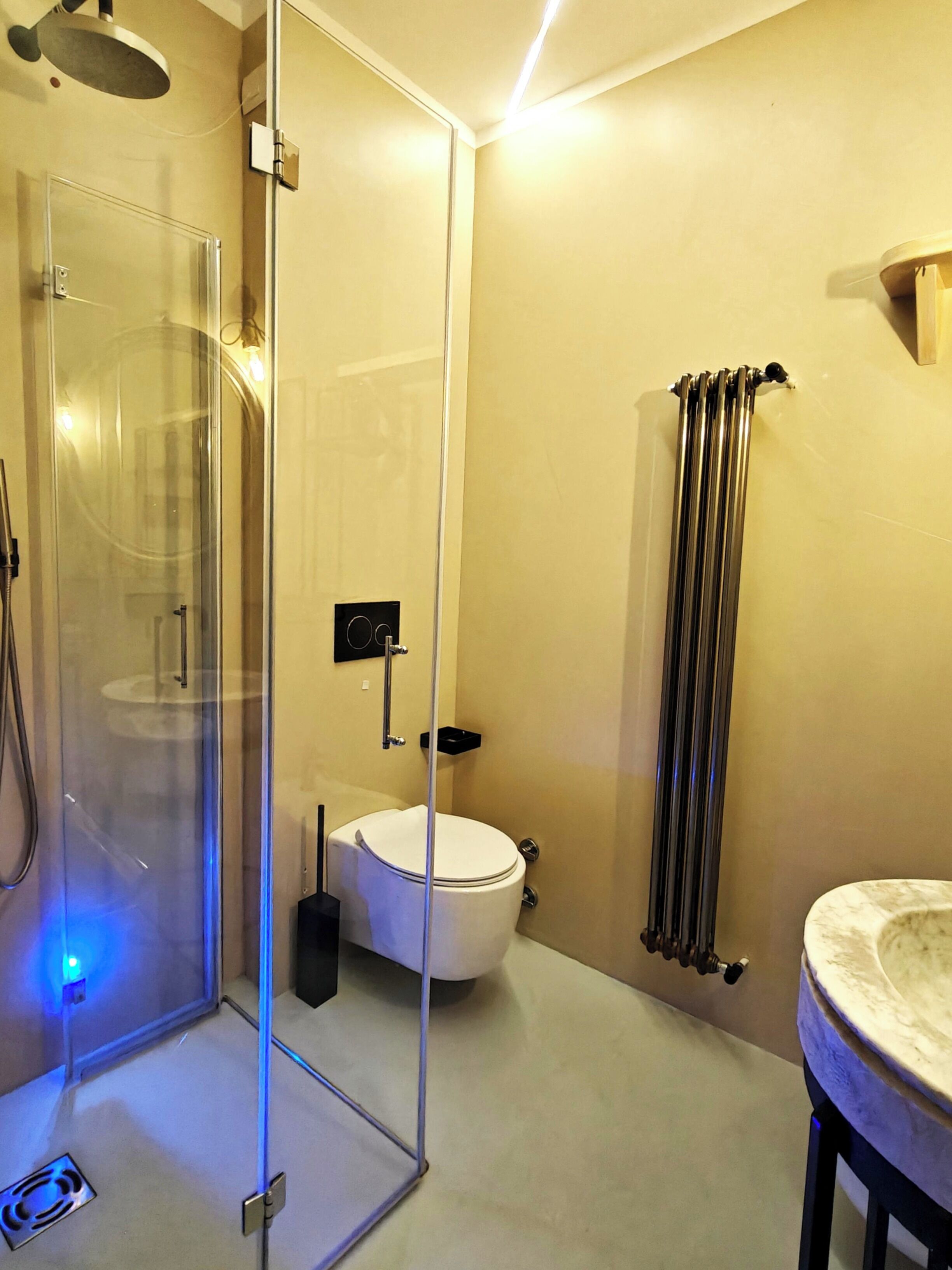 Une salle de bain moderne avec une douche à parois de verre, des toilettes, un radiateur et un lavabo en marbre.