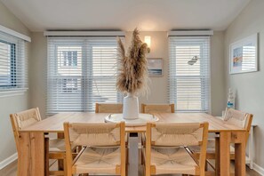 A dining area with a wooden table and chairs, a vase with dried plants, and a wall-mounted light. - Wildwood Backyard Oasis with pool (Wildwood)