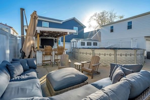 A backyard with a covered patio, outdoor furniture, and a barbecue area.