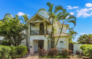 A two-story building with a balcony, surrounded by tropical vegetation. - Sugar Hill Birds Eye Villa - by Zenbreak (Holetown)