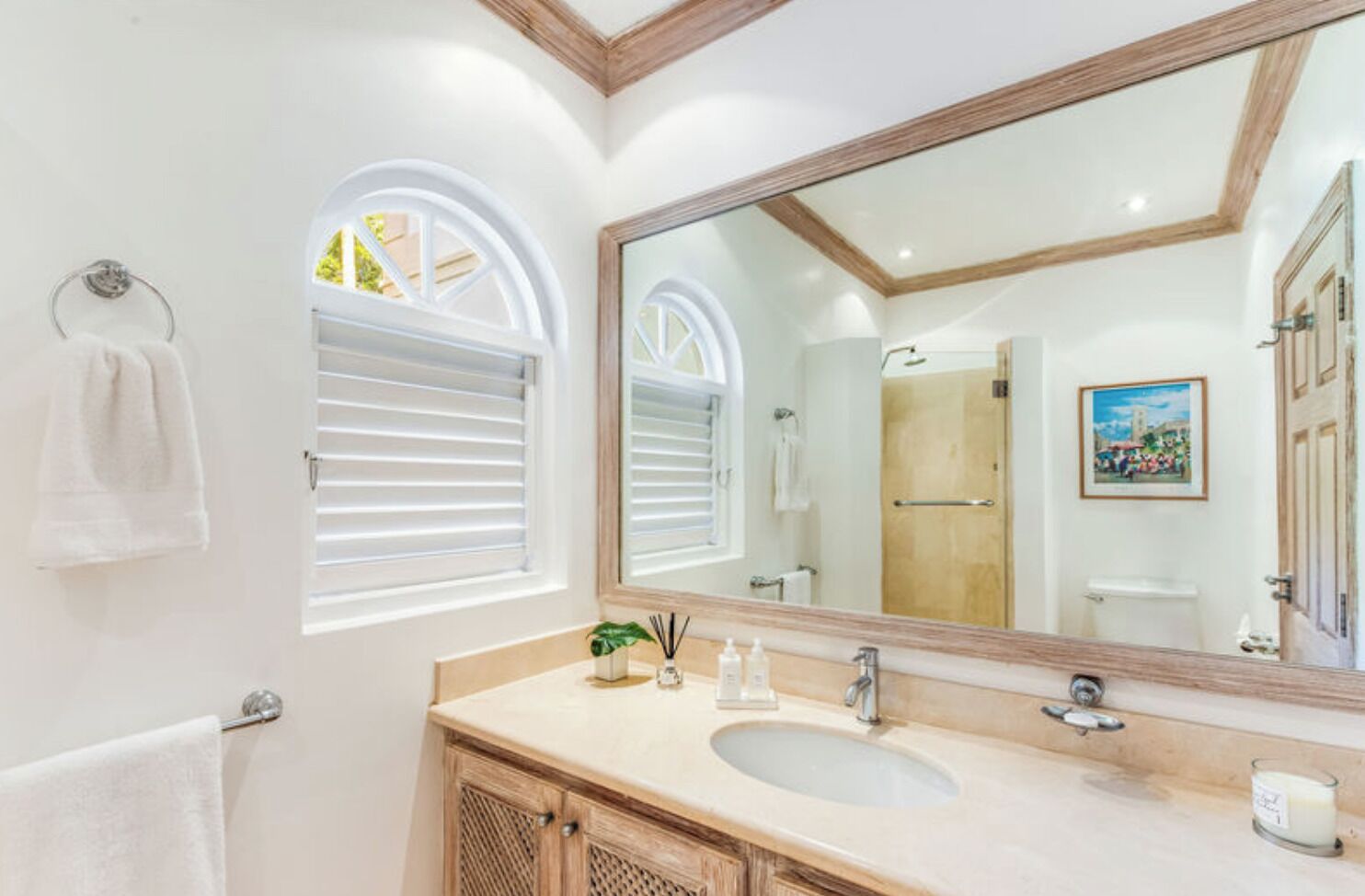 A bathroom with a large mirror, a sink, and a shower.