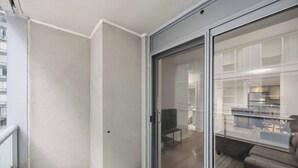 Un apartamento moderno con un cerramiento de vidrio corredera que da a una sala de estar con sofá y una mesa de comedor.