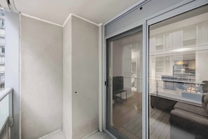 A modern apartment with a sliding glass door leading to a living area with a sofa and a dining table. - Steps to everywhere! Convenience at its finest! (Toronto)