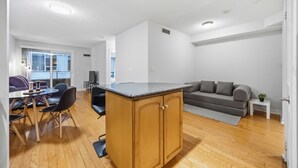 Una sala de estar moderna con un mueble de madera, un sofá gris, una mesa de comedor con sillas y un televisor.