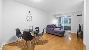 Una sala moderna con comedor, un sofá púrpura y un reloj de pared.