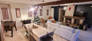 A living room with a white sofa, a foosball table, a Christmas tree, and a fireplace. - Charming gite la musette en champagne 10 people (Corrobert)