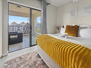 Une chambre d’hôtel avec un lit, une vue sur l’extérieur et un balcon agrémenté d’un fauteuil suspendu.