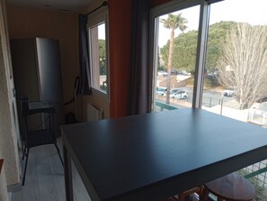 Ein Zimmer mit großem Fenster, Flachbildfernseher, Schreibtisch und Stuhl.