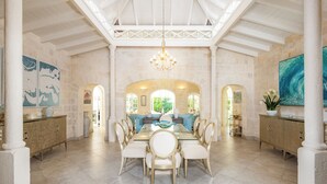 A spacious dining area with a high ceiling, chandeliers, and a view of the garden through large windows. - Royal Westmoreland Lonetrees - by Zenbreak (Westmoreland)