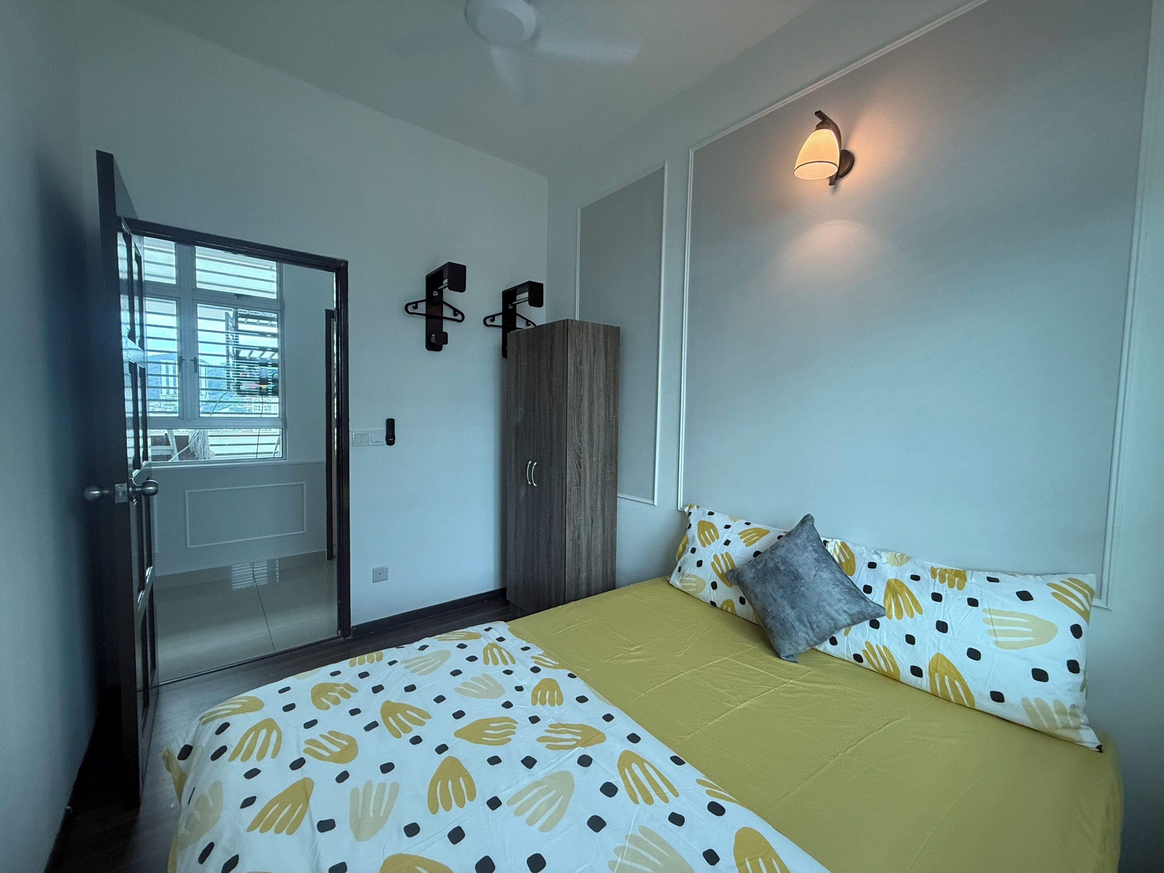 A bedroom with a bed, a wardrobe, a door, and a wall-mounted light fixture.