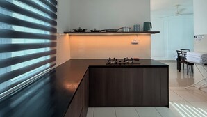 A modern kitchen with a dark countertop, a built-in stove, and a small island. - SPICE Skyview Luxe Tunas 4B3B (Bayan Lepas)