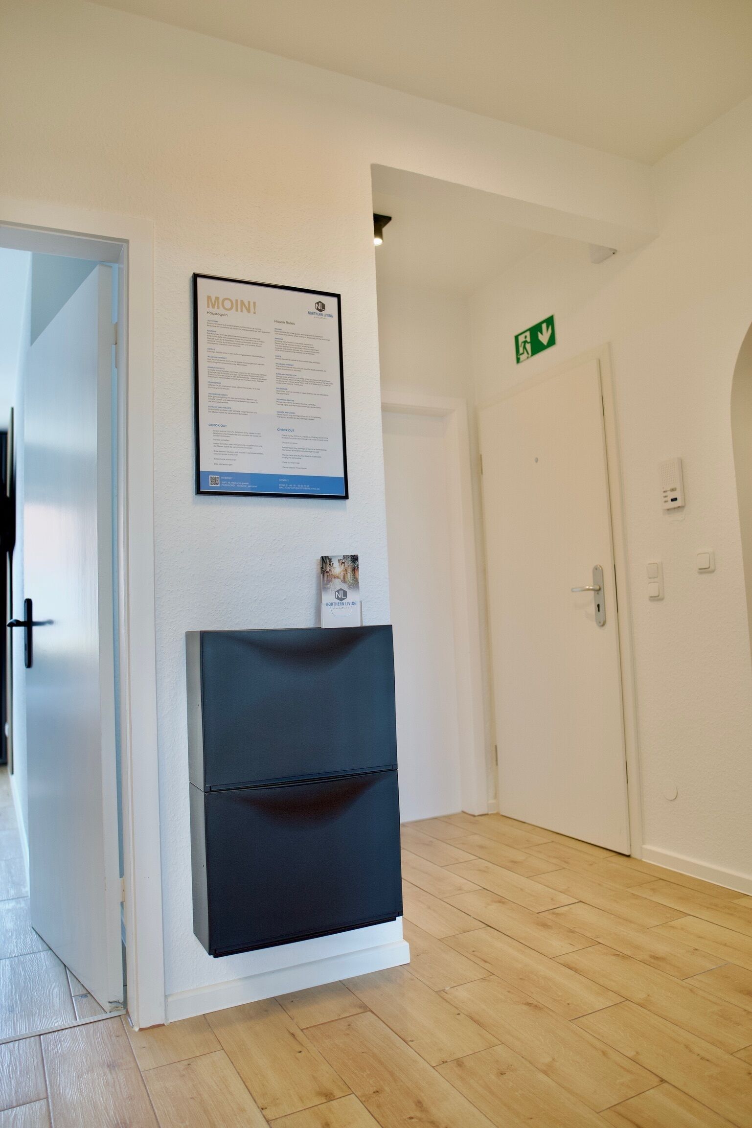 Ein Korridor mit einer weißen Tür, einem gerahmten Schild an der Wand und einem Kamin.