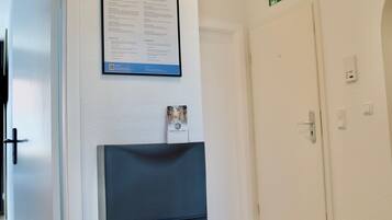 Ein Korridor mit einer weißen Tür, einem gerahmten Schild an der Wand und einem Kamin.