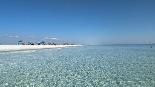 A beach with clear shallow water, a sandy shore, and some beach umbrellas. - New Build, Modern Studio. Minutes from the Beach. (Navarre)