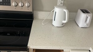 A kitchen with a stove, toaster, and drawer with utensils. - New Build, Modern Studio. Minutes from the Beach. (Navarre)