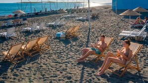 A beach with sun loungers, umbrellas, and a building in the background. - Club Aperion Beach hotel - All inclusive (Manavgat)