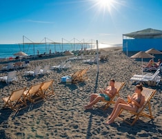 Playa privada, arena negra, sillas reclinables de playa, sombrillas