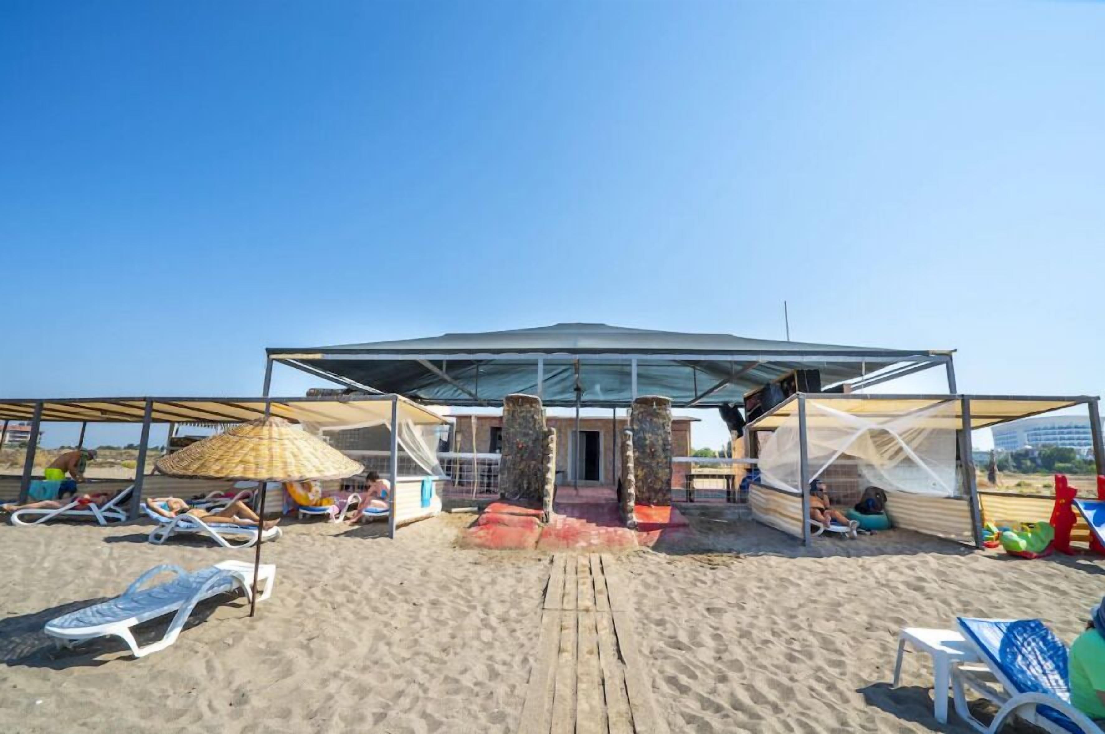 Een strandgebouw met overdekte ingang, ligstoelen en een schaduwrijk gebied.
