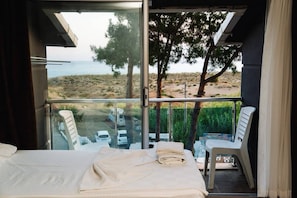 A bedroom with a balcony overlooking a beach, a bed, and a table with chairs. - Club Aperion Beach Hotel (Manavgat)