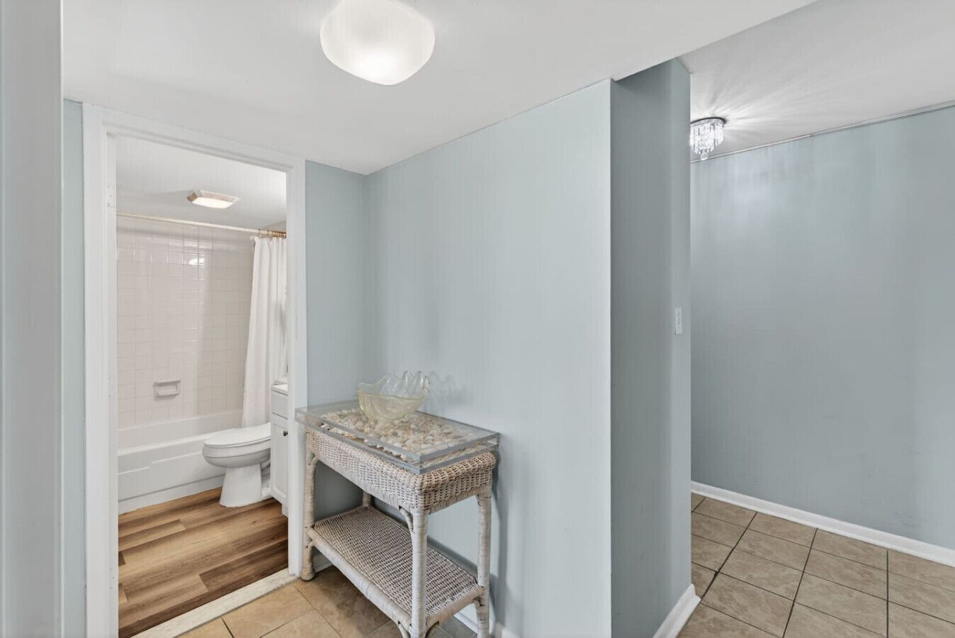 Une salle de bain équipée d’une douche, de toilettes et d’un meuble-lavabo en osier avec un récipient en verre.