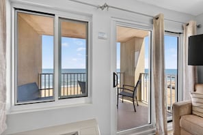 Une chambre avec un balcon, une chaise, un canapé et une télévision.