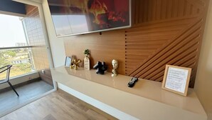 Ein modernes Hotelzimmer mit Balkon, einem wandmontierten Flachbildfernseher, einer Wandpaneele aus Holz und einem kleinen Tisch mit Dekoration.