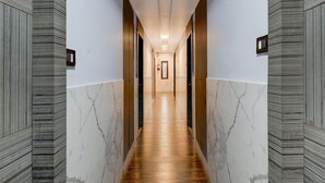 Un couloir moderne avec un plancher en bois, des murs en marbre et un luminaire central.