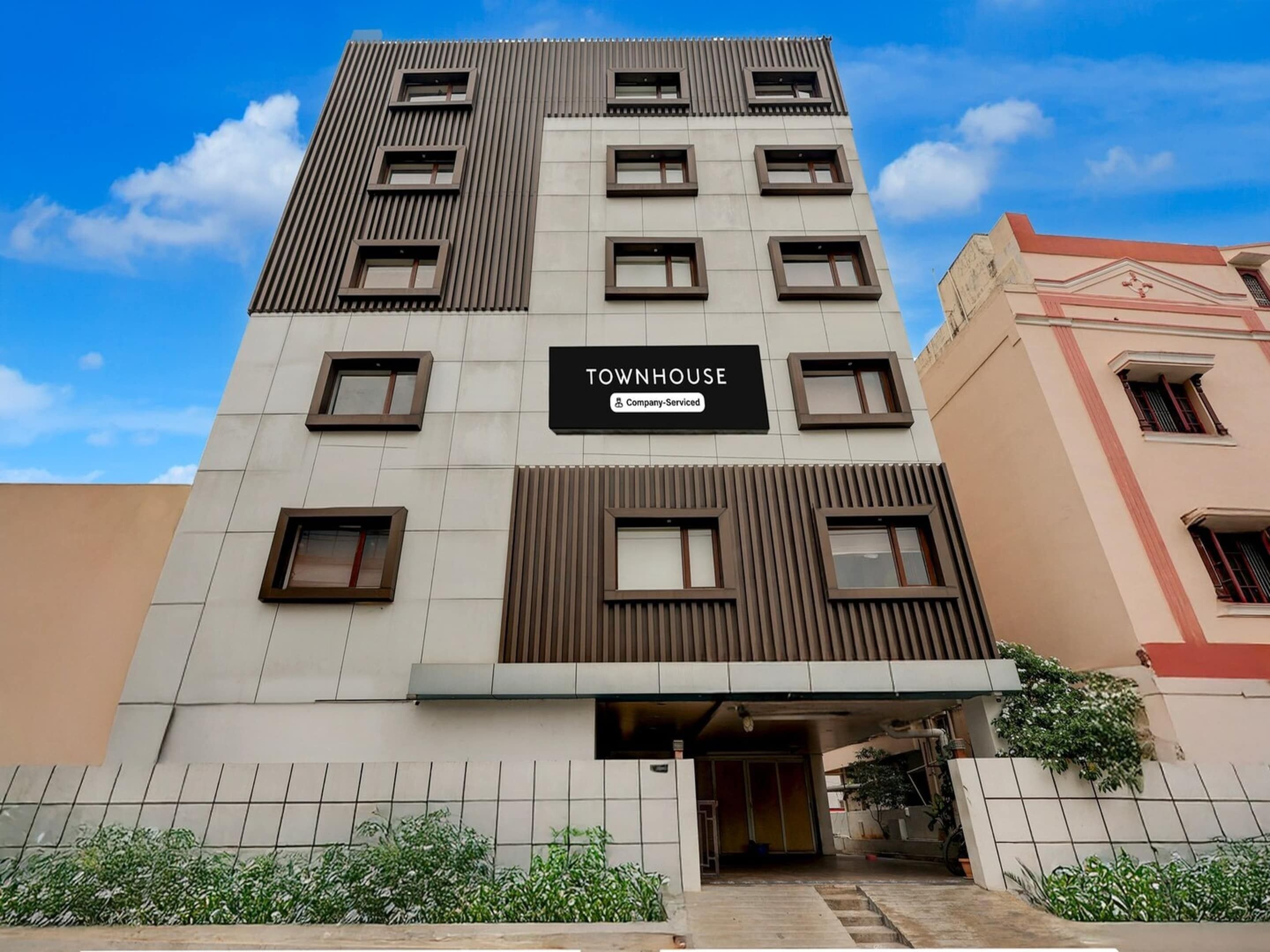 Un edificio a più piani con un'insegna che recita 'TOWNHOUSE Company-Serviced'.