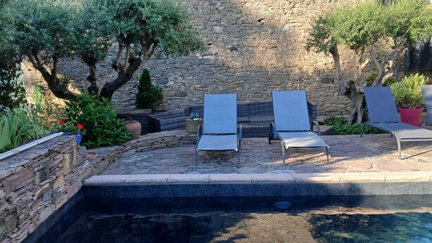 A stone wall, a swimming pool, and lounge chairs. - Bed and breakfast with swimming pool (Trausse)