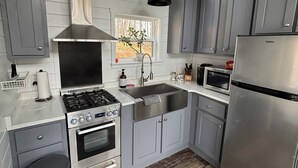 Een moderne keuken met grijze kastjes, roestvrijstalen apparatuur, een gasfornuis en een inbouwoven.
